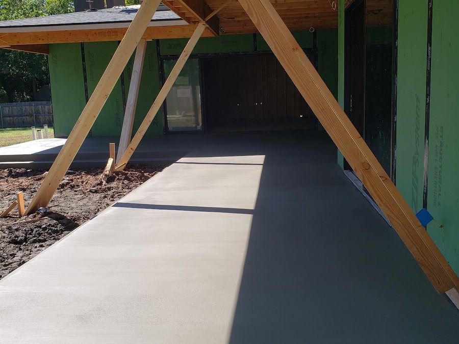 Smooth concrete walkway and patio extension beside a brick home at sunset.