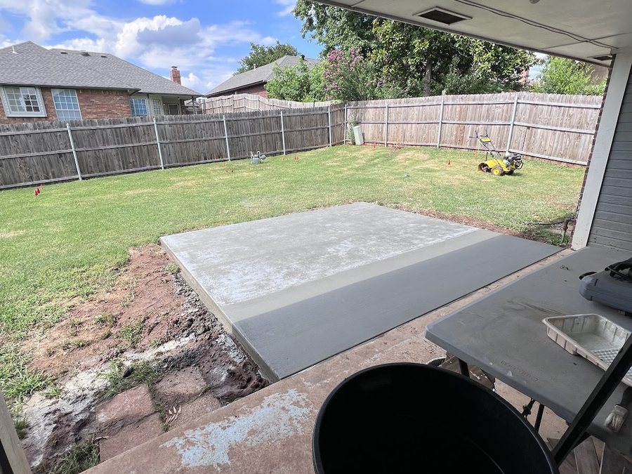 Fresh concrete walkway and entry slab beneath the framing of a covered addition.
